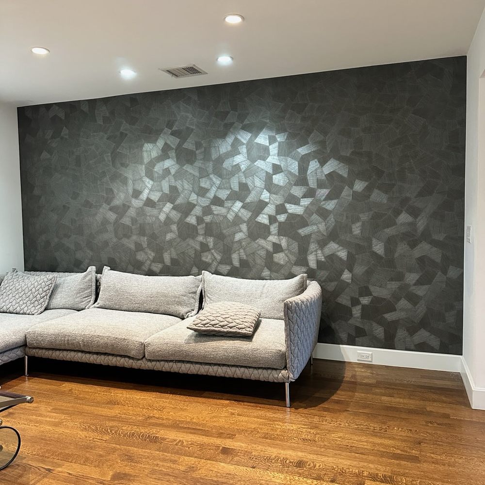 Dark textured wallpaper feature wall behind a living room sofa